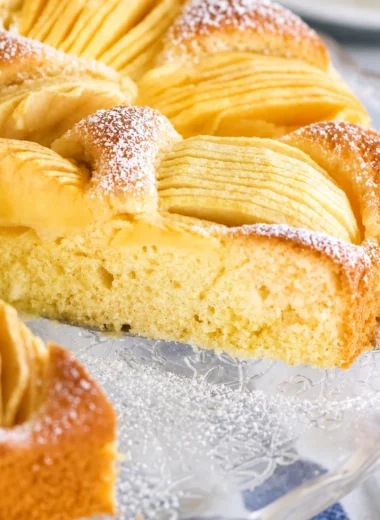 Slice of traditional German apple cake (apfelkuchen) with fresh apples and custard.