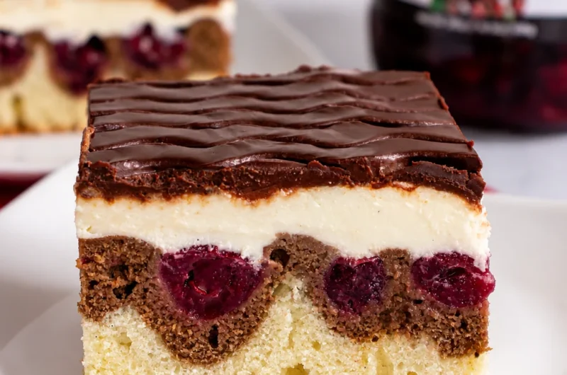 A slice of Deliciously Rich German Donauwelle cake with layers of chocolate, vanilla, and cherries.