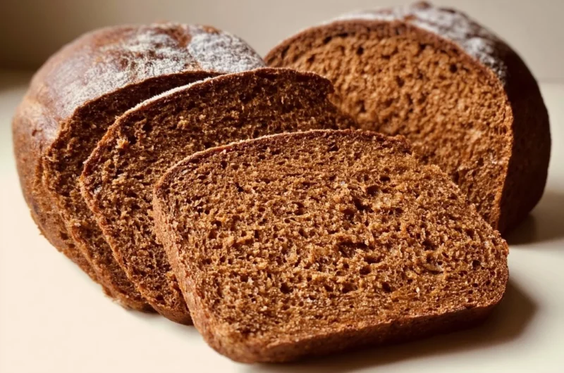 Freshly baked Schwarzbrot, a traditional German rye bread, on a wooden table.